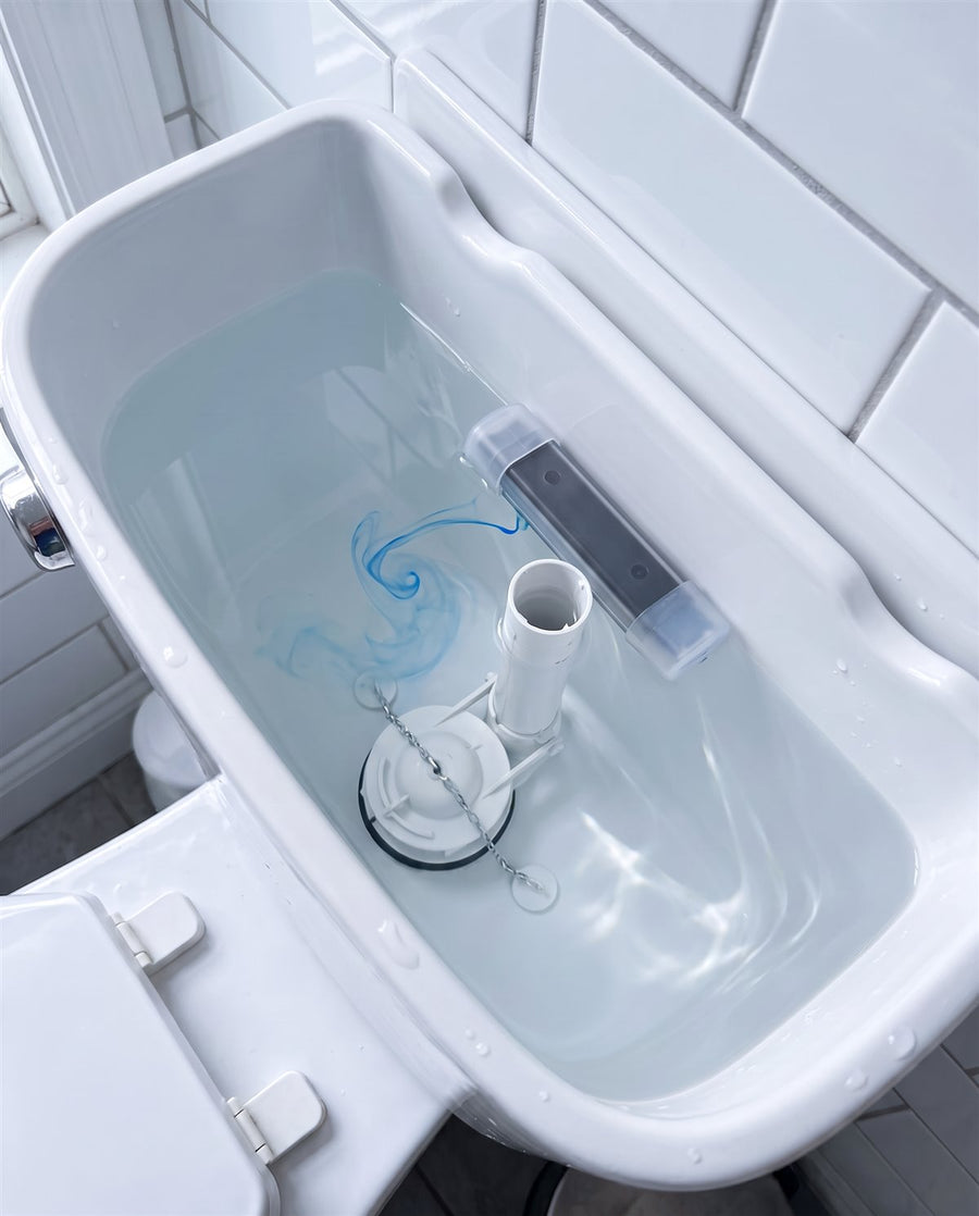 The same toilet tank cleaned, with clear water and a Tidecroft dispenser against the inside wall